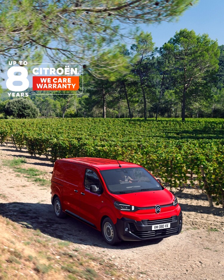 Three‑quarter front view of a red Citroën Jumpy driving on a rural road, showing robust design, driving comfort, versatility and confident presence.